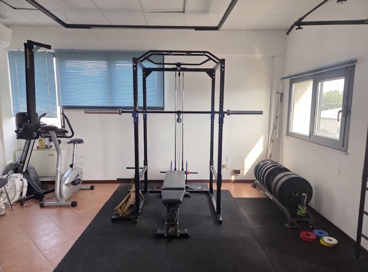 Sala attrezzata con power rack, panca e attrezzatura cardiovascolare